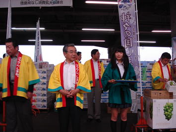 市場関係者にシャインマスカットの試食を勧める知事の写真