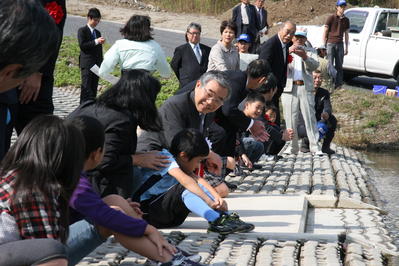 児童と一緒に稚魚の放流をする知事