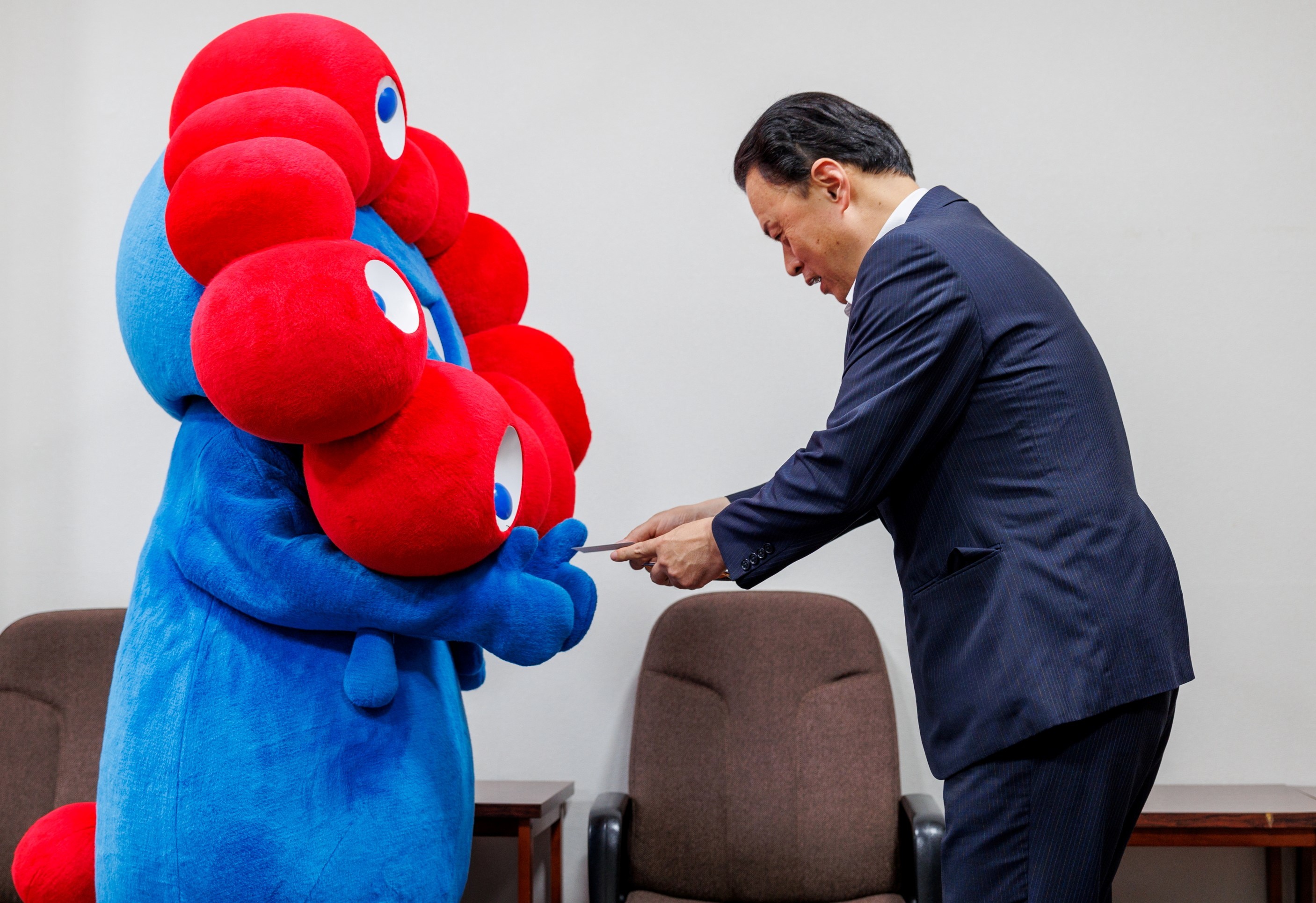 万博公式キャラクター『ミャクミャク』と名刺を交換する知事
