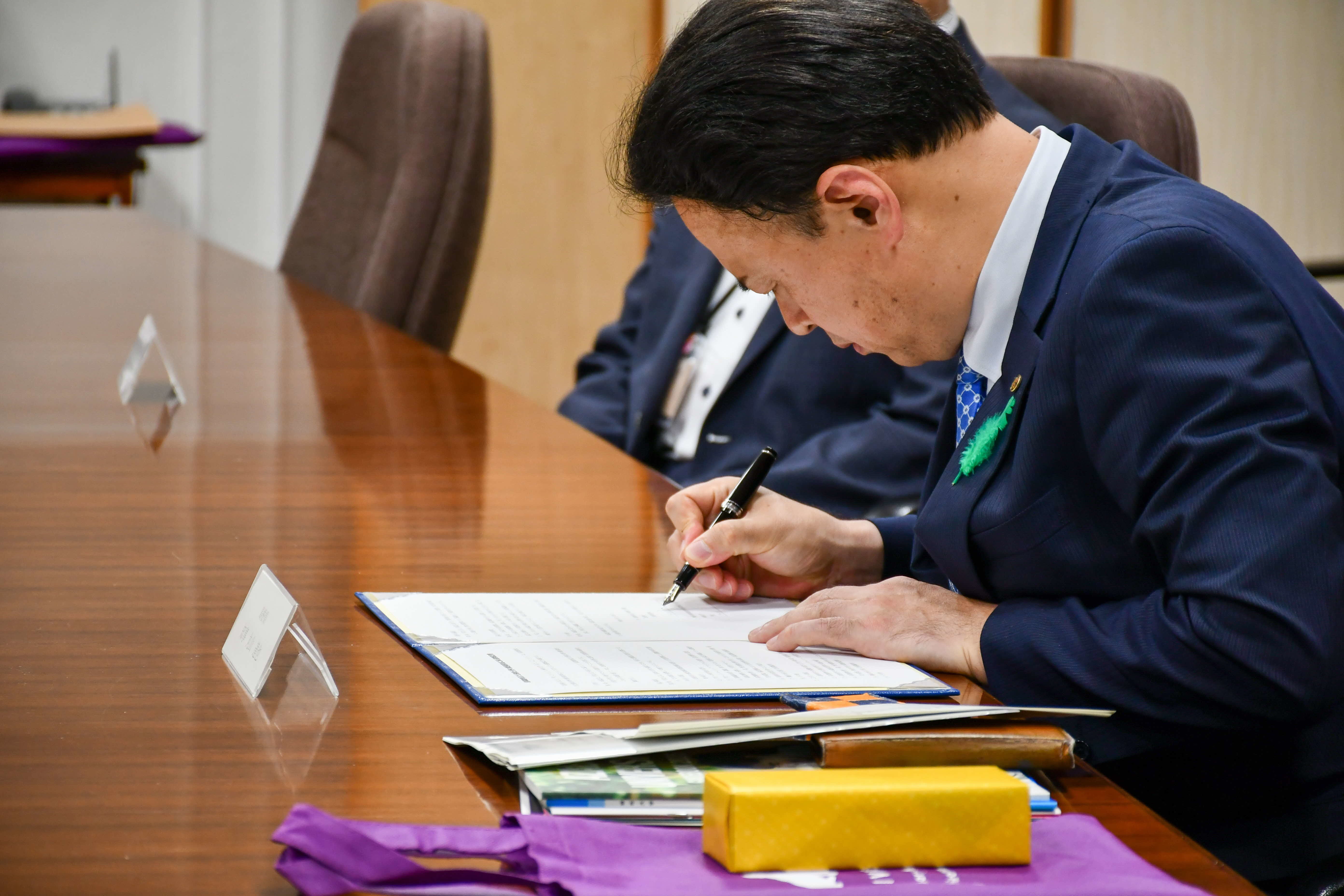 協定書にサインをする知事