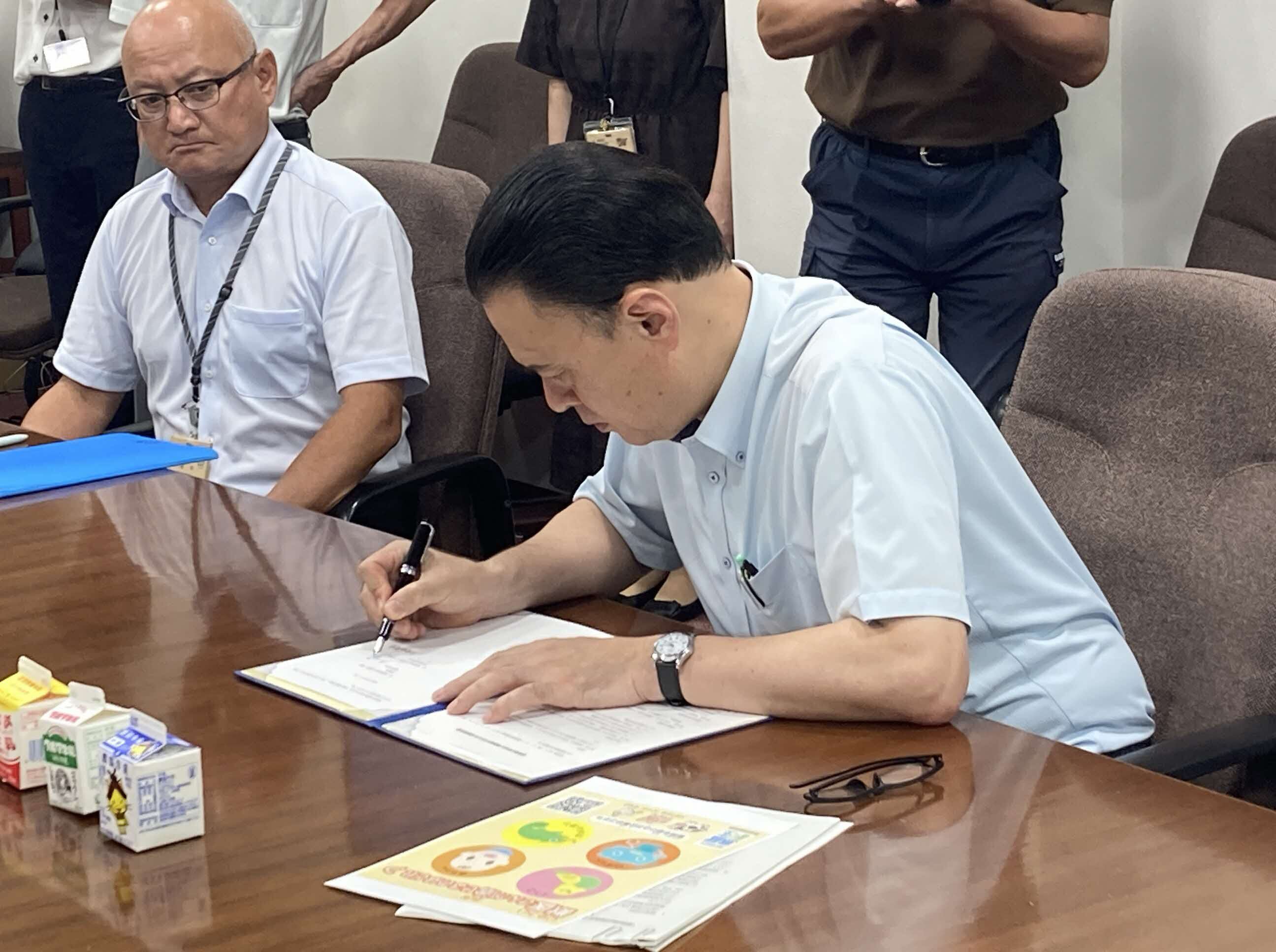 協定書にサインをする知事