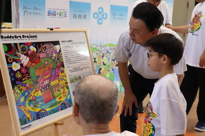 バディアートのイラスト提供者から説明を受ける知事